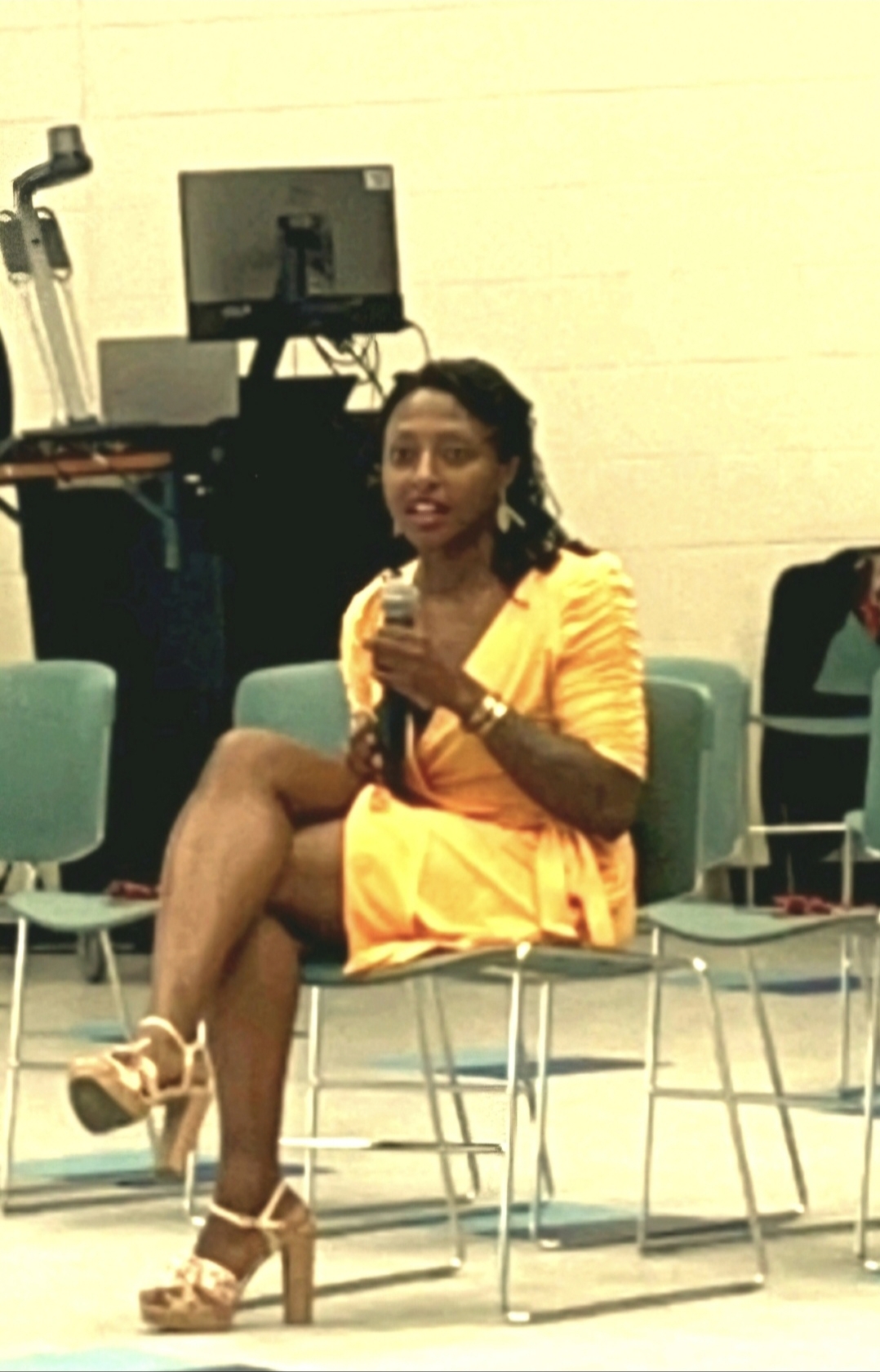 Sarah Livingstone facilitating a discussion in orange dress with microphone
